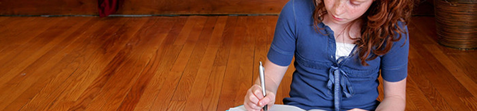 Girl sitting writing hardwood floor